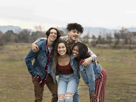 A group of four young people, two men and two women, in a field