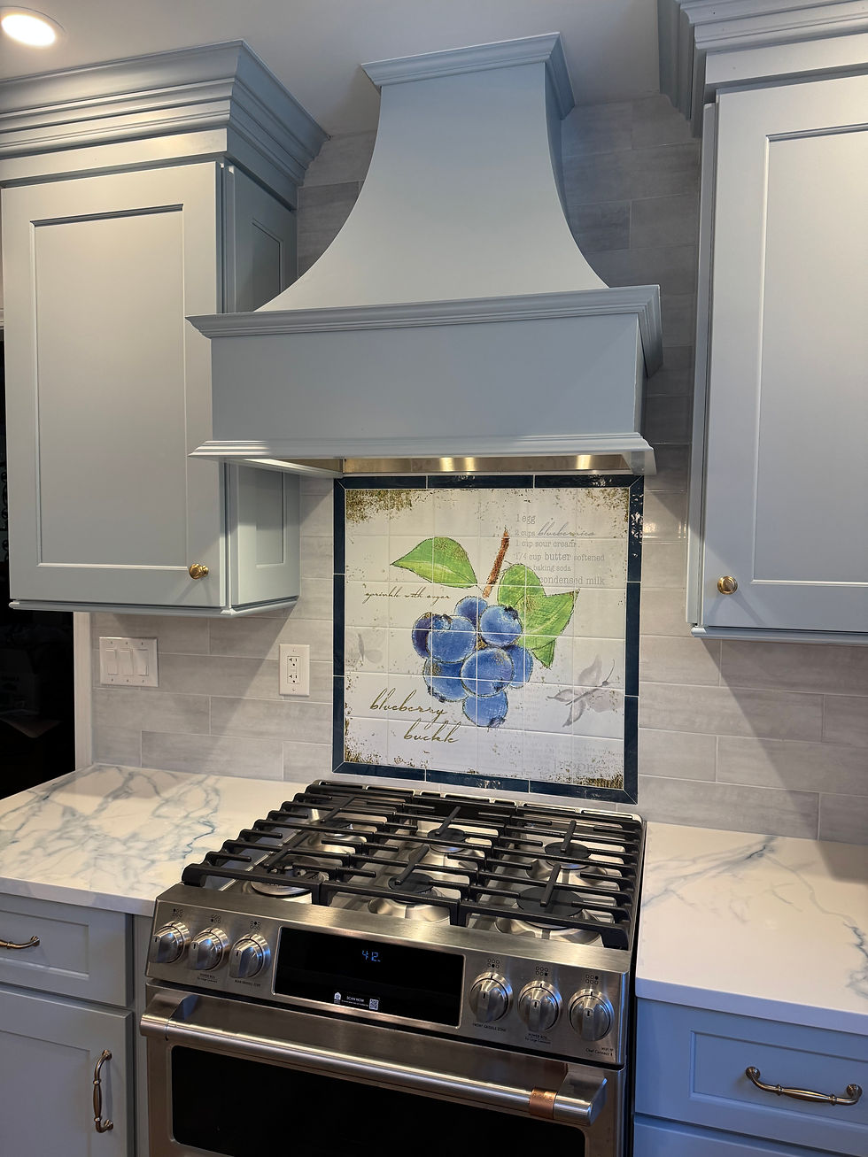 Decorative Range Hood and Unique Blueberry Mosaic with gorgeous blue and white quartz countertops