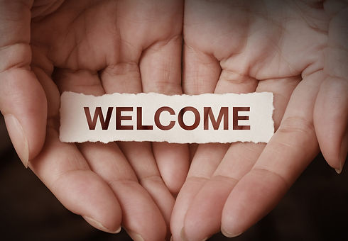 Two hands cupped together holding a scrap piece of paper with the word Welcome in capital letters.