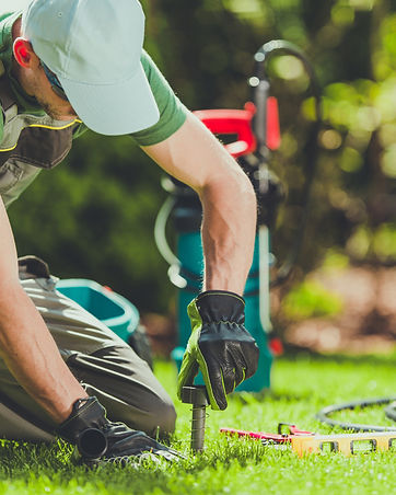 A SprinklerPro working on a lawn with tools, performing custom sprinkler system installation and repair.