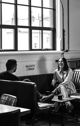 Man and woman sat on sofa in office environment laughing