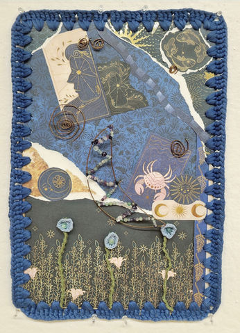 Rectangular mixed-media assemblage bordered with dark blue crochet. Layered blue, gray, cream, and gold patterned papers contain celestial and figurative imagery, copper wire spirals, strands of colored beads, and three crocheted flowers on green stems.