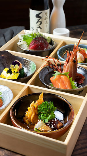 Japanese cuisine assortment with several small dishes displayed in a wooden box.