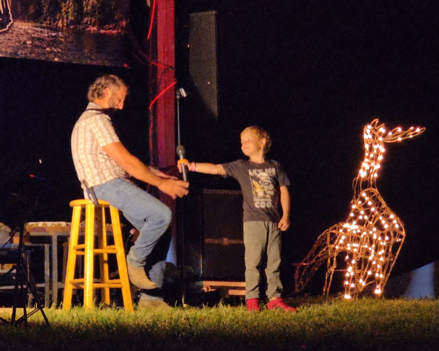 Dustin and Konnor onstage at Redneck Rendezvous, sharing the microphone as Konnor tells his jokes.