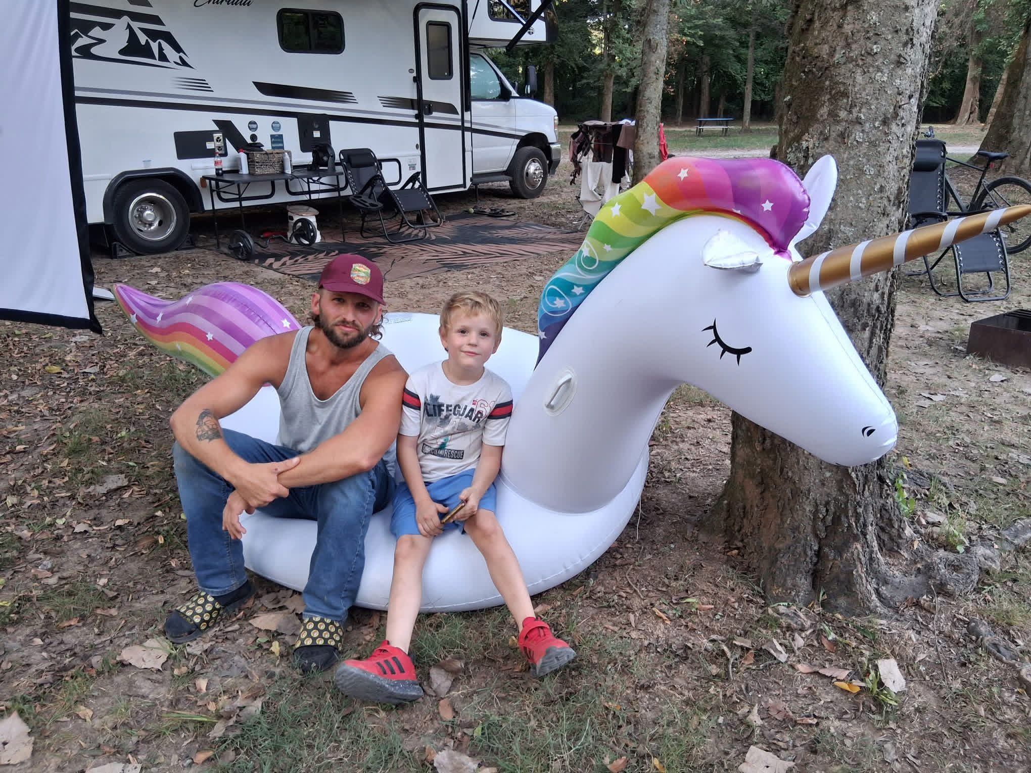 Dustin and Konnor sitting on Dolly the inflatable unicorn beside the RV.