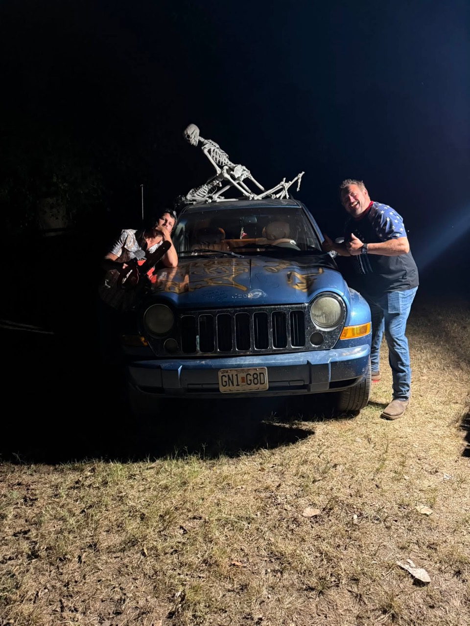 Dustin and Andy beside Cheyenne’s spray-painted Jeep, with skeletons posed on its roof.