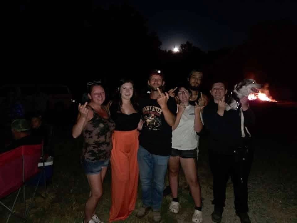 Members of the Current River float crew posing with Dustin and giving the camera the middle finger at night.