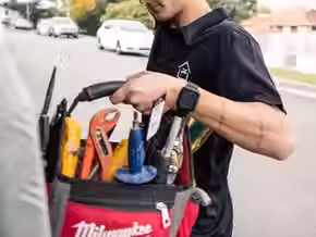 Plumber repairing a pipe with professional tools.