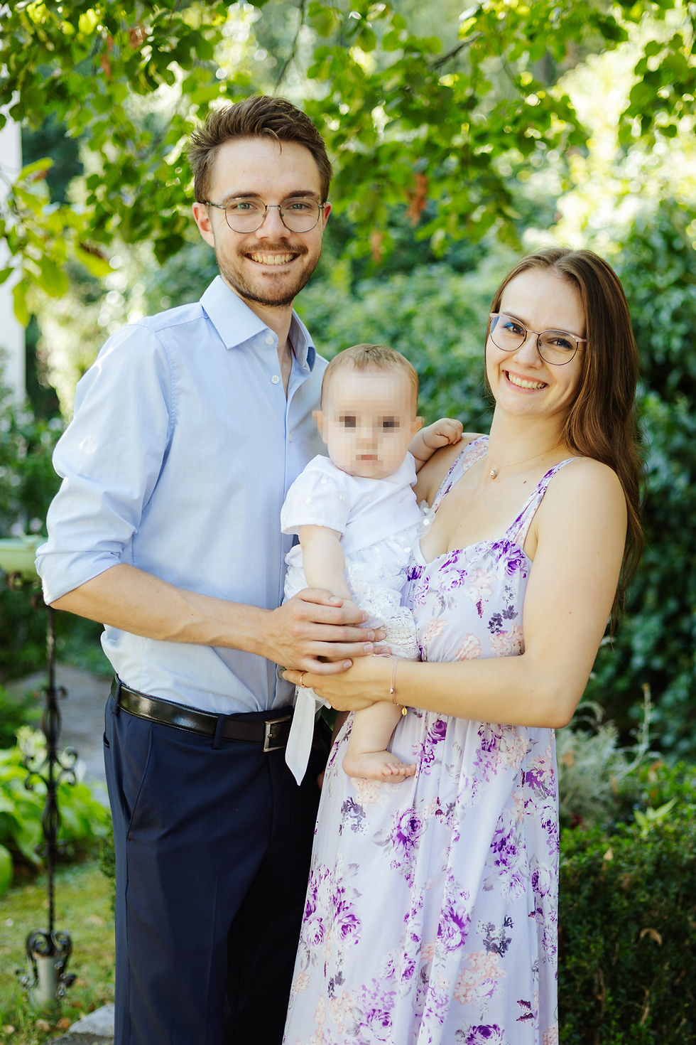 Eltern halten ihr Baby bei einem entspannten Familienshooting im Grünen.