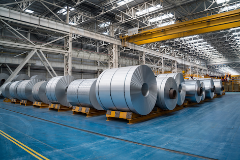 large industrial steel bundles held together by black strapping in factory setting