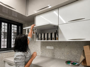 Person reaching for cabinet in modern kitchen.