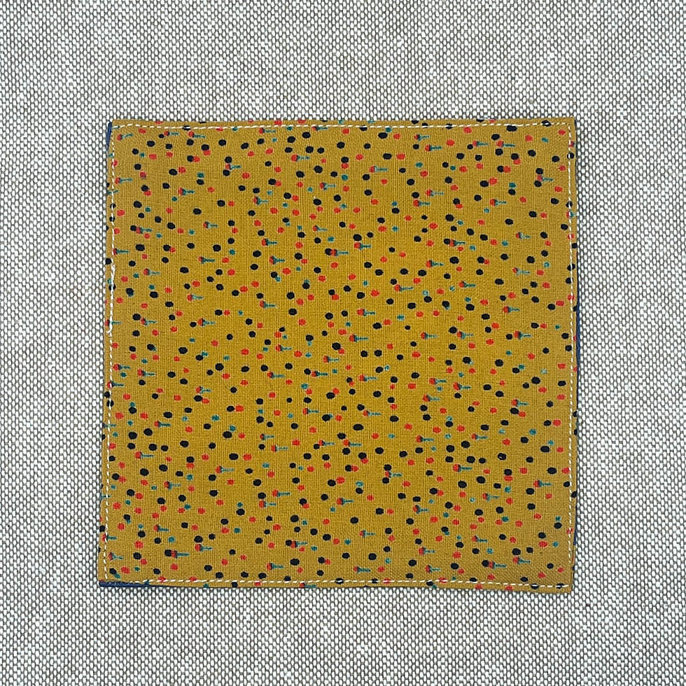 Untersetzer aus Stoff mit blauen Blüten auf dunkelblauem Grund und senffarbener Rückseite mit Punkten