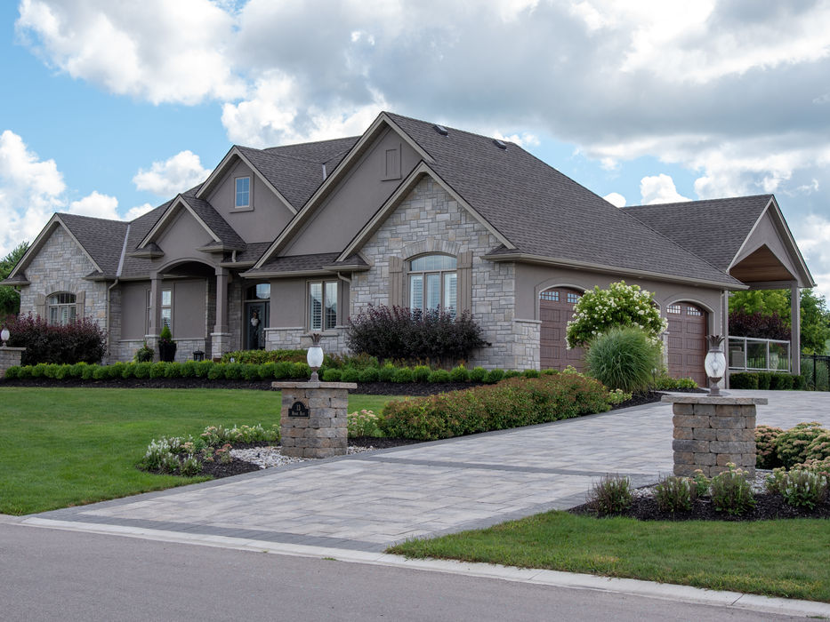 Large-scale interlock driveway using Oak's Rialto pavers in Champagne with decorative stone pillars and custom lighting.