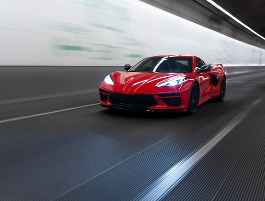 Passenger-side angle of Torch Red Corvette parked near trees in Redmond Washington