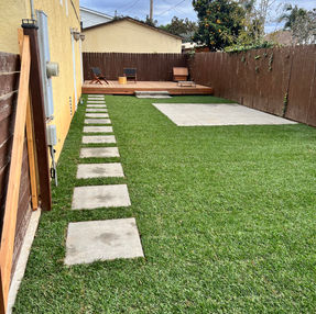 Lawn renovation with wood deck, green grass, and concrete pavers