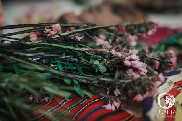 Delicate pink flowers rest on a colorful woven textile at Lunita Jungle Retreat in Playa del Carmen, Mexico, capturing the serene and natural essence of this tranquil retreat center.