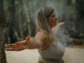 A participant embraces an energetic cleansing ritual amidst the tranquility of nature during a personal development retreat.