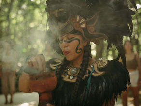 A serene moment unfolds during the blessing ceremony at Lunita Jungle Retreat Center in Mexico, where an intricately dressed woman channels ancestral spirit, enveloping the yoga retreat in sacred smoke.