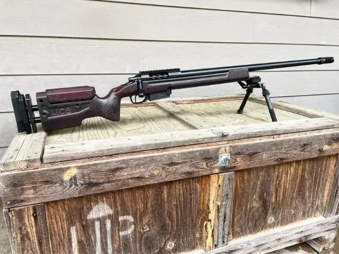 Custom precision rifle with wood stock on a wooden crate