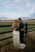 Bride and groom kissing by fence, ranch wedding