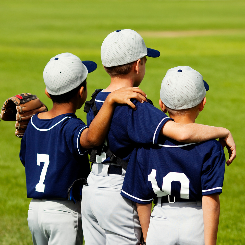 Three young baseball players, one with arm around another