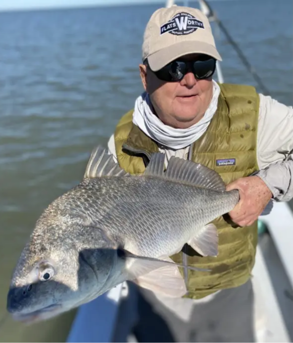 Man holding black drum fish on boat