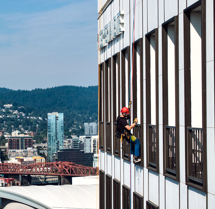 Man rappelling down the side of a tall building with the word 'REGAS'.