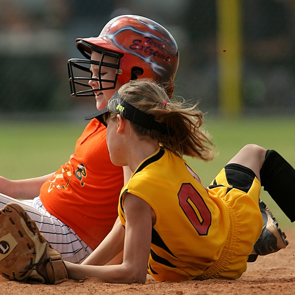 Softball player slides into base as opponent waits