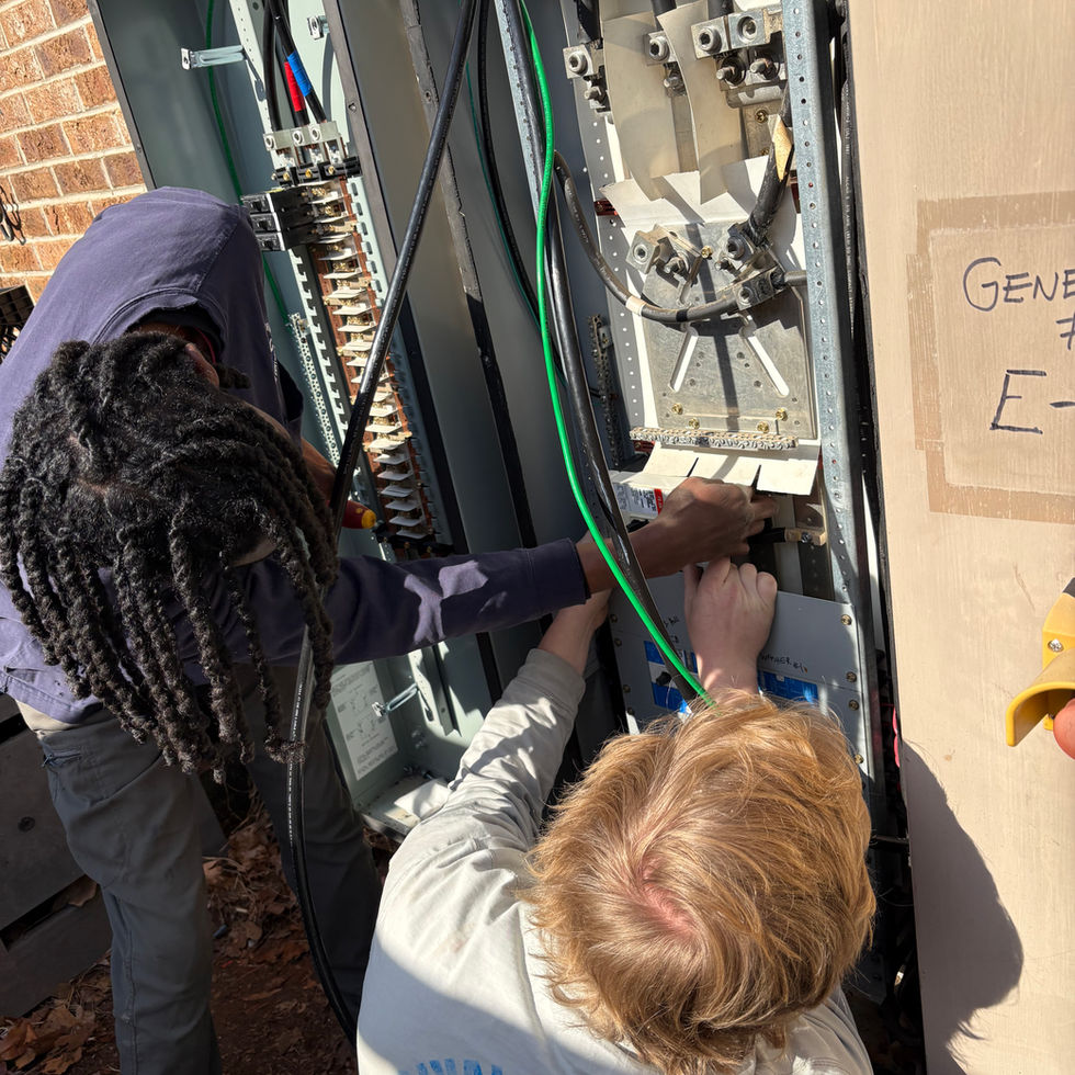 Two workers installing wiring into an outdoor electrical panel.