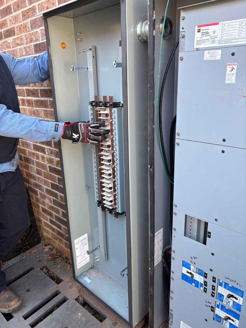 Gloved hand working on open outdoor electrical panel
