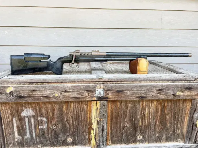 Custom precision rifle resting on a wooden chest