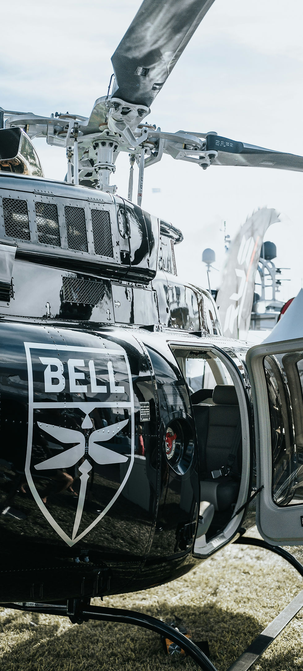 A close-up of a Bell helicopter, highlighting its logo and detailed rotor assembly, displayed in an outdoor setting
