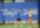 A tennis coach and player stand near the net on an outdoor court with a large “Beijing 2008” banner in the background.