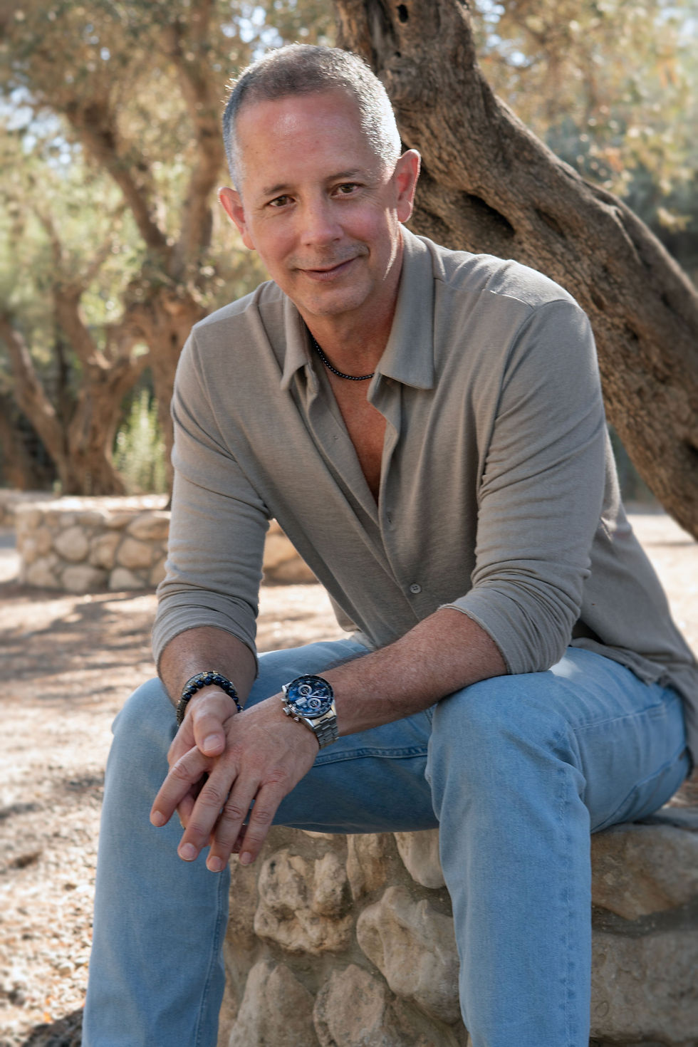 Portrait of Pablo, transformational coach, sitting outdoors and smiling warmly during a reflective moment.