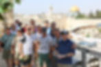 A group of men posing together at a viewpoint overlooking the Western Wall and the Dome of the Rock in Jerusalem.