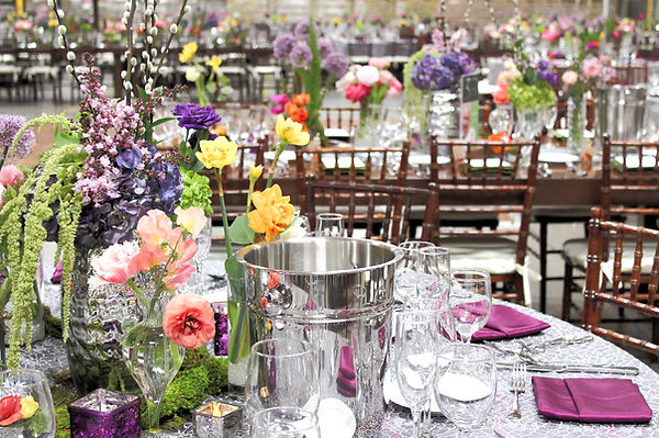 Nonprofit Event that too place in a storage warehouse, photo includes desugned tables, floral design, and chairs
