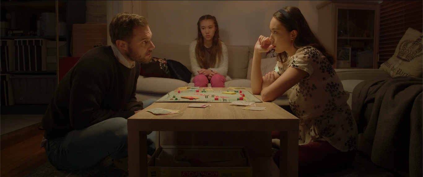 family siting around table playing monopoly argument