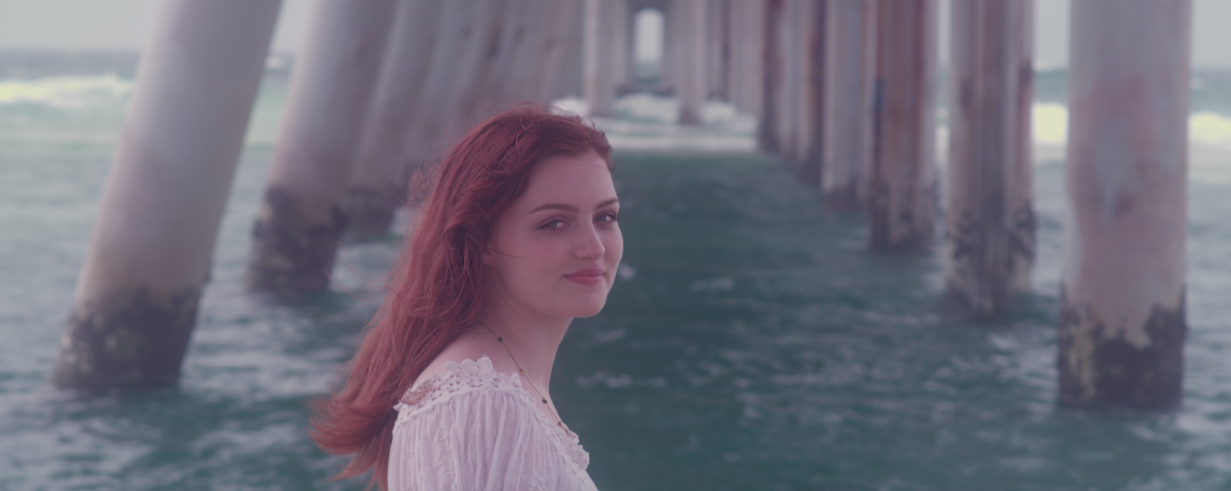 red haired woman by the sea under a dock the spit