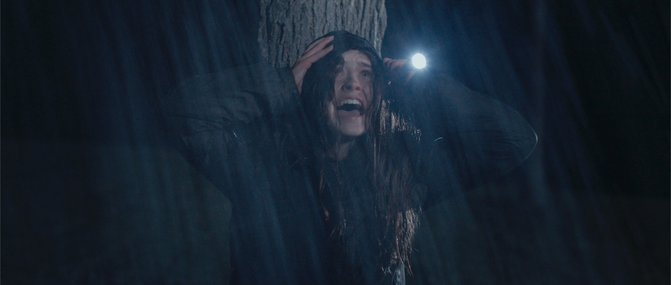 teen girl in rain yelling with flashlight in hand outdoors