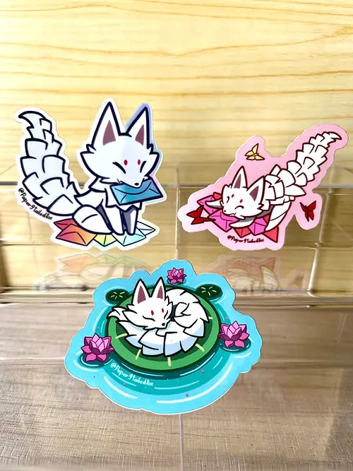Three cartoon fox stickers on a wooden surface