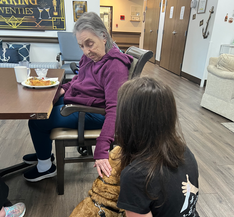 girl in black shirt showing a old lady a rescue dog and she's knelt down