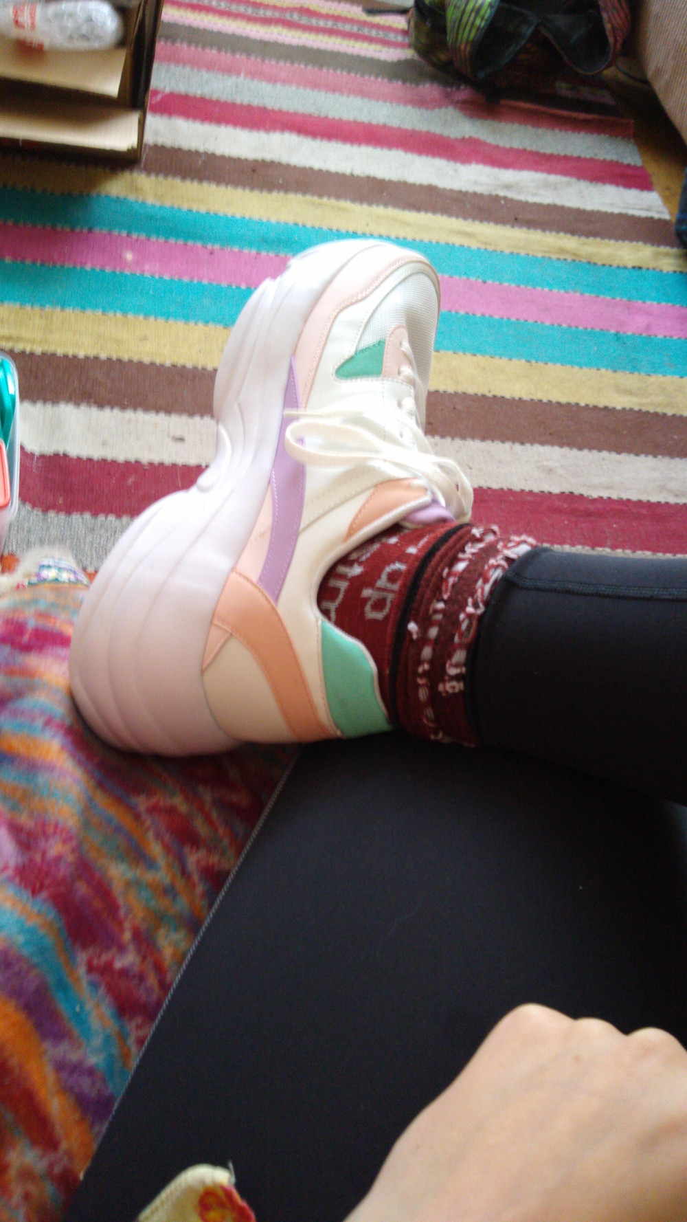 A chunky 90s style trainer with pastel colour detail on Daisy's massive foot