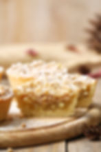 Nahaufnahme von Zwetschgenkuchen-Schnitten mit goldbraunem Mürbeteigrand, weißer Vase im Hintergrund, weich und appetitlich.