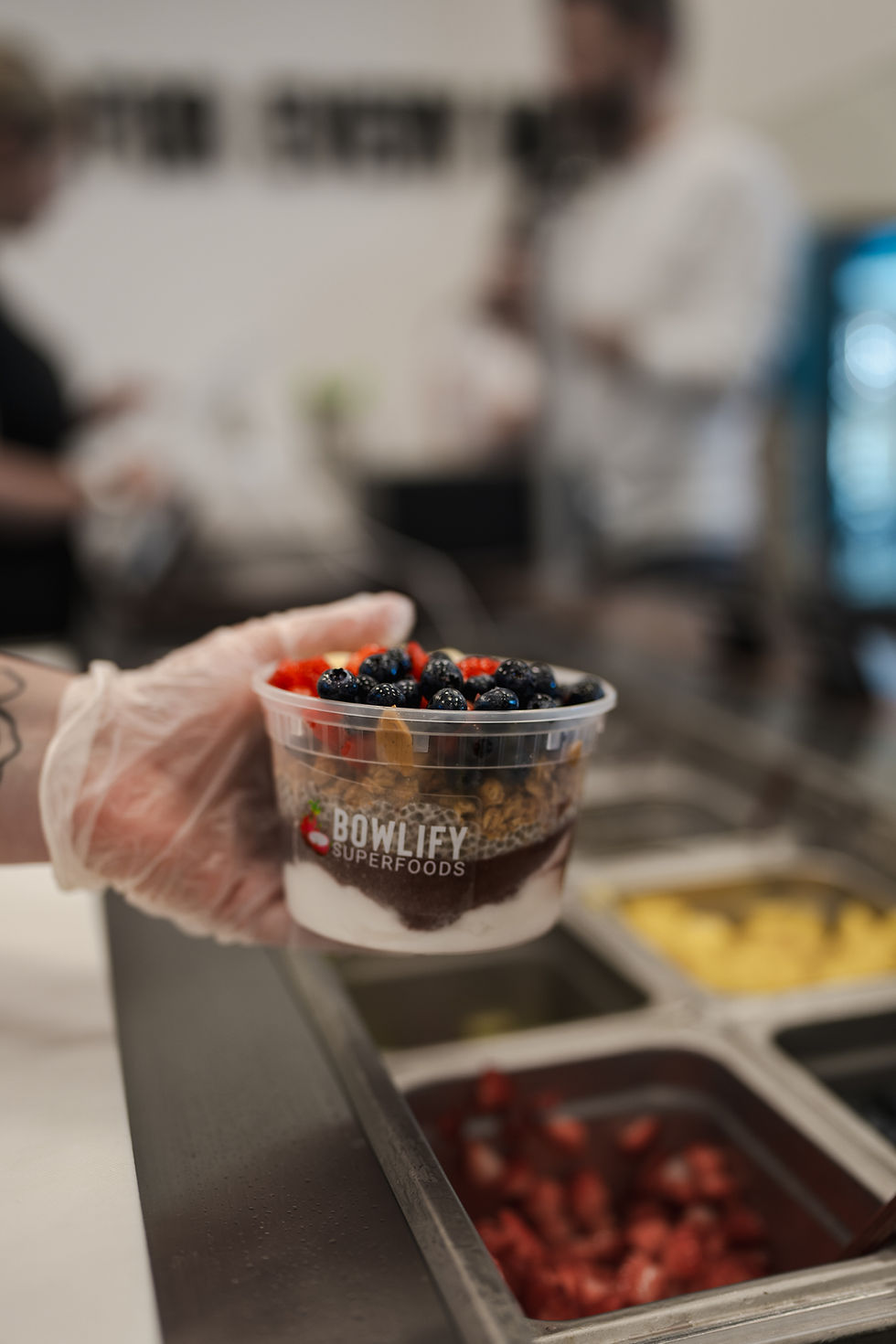 An acai bowl with coconut and acai base, topped with granola, peanut butter, strawberries, and blueb