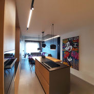 Open space moderno con finiture in legno naturale e dettagli in nero, arredato con mobili di design