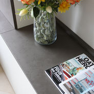 Dettaglio di arredamento con vaso decorativo in vetro trasparente su tavolino in legno scuro.