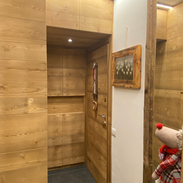 Ingresso di montagna con pavimento in legno, pareti in pietra naturale e dettagli rustici