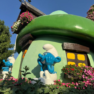 Dubai Miracle Garden’daki Şirinler Köyü temalı çiçeklerle süslenmiş ev ve Şirin heykelleri.