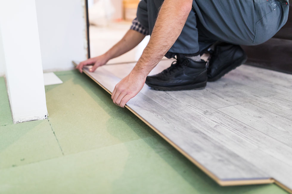 Close-up of a professional installing a luxury vinyl plank over a green underlayment, aligning the flooring into place.