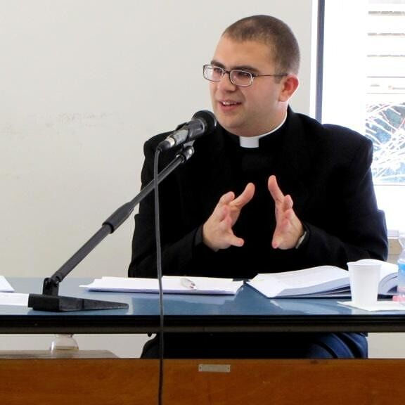 Fr. Dominic Sultana speaking into a microphone